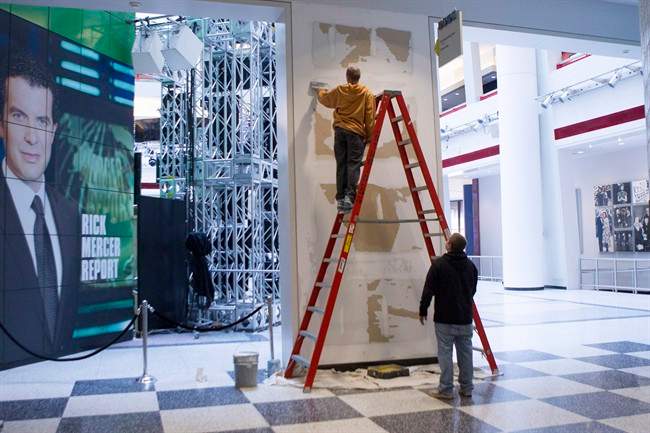 Workers scrape a wall which had a publicity photo of former CBC radio host Jian Ghomeshi in the broadcasting corporation's Toronto offices on Monday October 27, 2014.