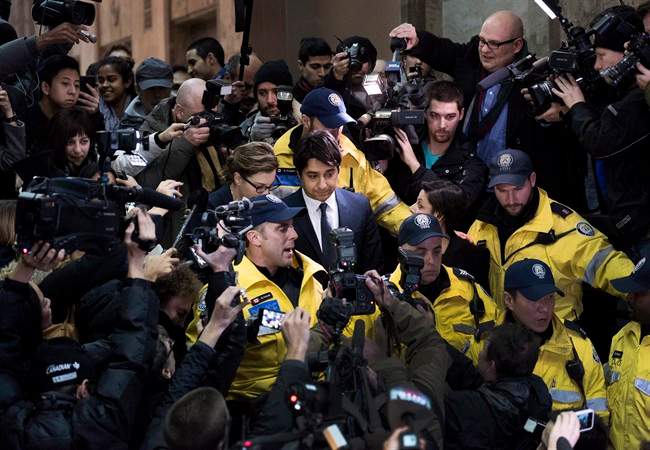 Former CBC Radio host Jian Ghomeshi, centre, is escorted out of court after being released on bail in Toronto on Wednesday, November 26, 2014.