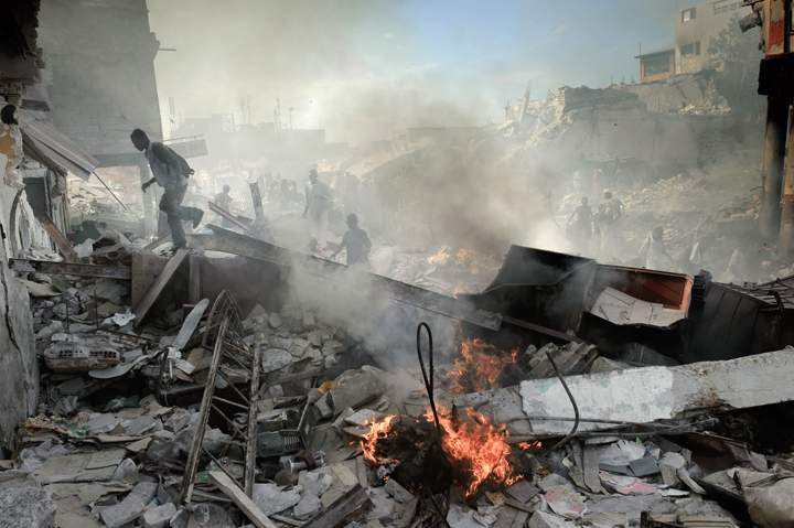 Haitians walk through collapsed buildings near the iron market in Port-au-Prince on January 31, 2010. 