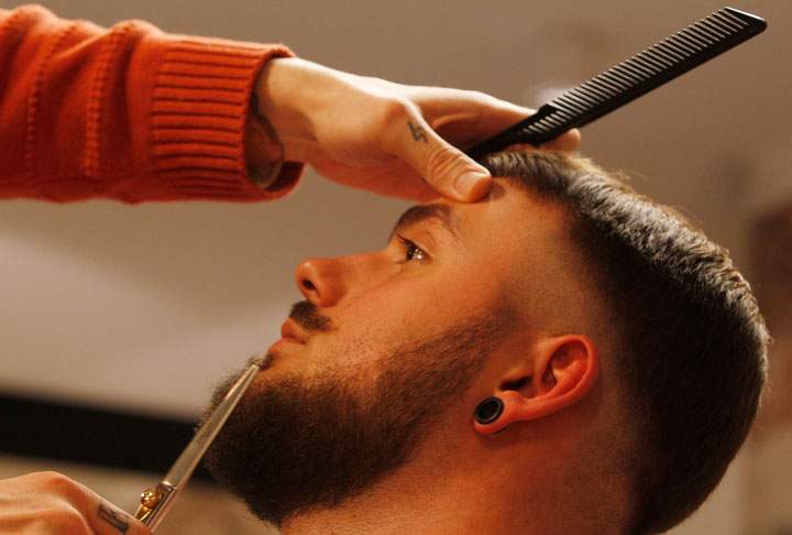 In this Nov. 13, 2014, photo, Salvador Chanza, 31, a master barber from Spain, who also calls himself Lord Jack Knife, trims the beard of Jakub Marczewski, with scissors at the Barberian Academy & Barber Shop in Warsaw, Poland. Chanza was sharing his expertise at the shop, which opened last month in Warsaw as beards are enjoying a comeback in the Polish capital.