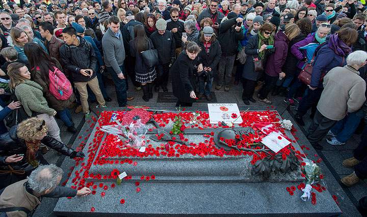 People place poppies at the Tomb of the Unknown Soldier following the Remembrance Day ceremony at the National War Memorial in Ottawa on Tuesday, Nov. 11, 2014.