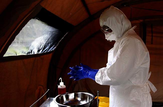 FILE - In this Sept. 24, 201, file photo, nurse Dalila Martinez, trainer of the Cuban medical team to travel to Sierra Leone, washes her gloved hands during a practice drill at a training camp, in Havana, Cuba. Cuba's health ministry is sending more than 160 health workers to help stop the raging Ebola outbreak in Sierra Leone in early October. Cuba says a member of the 165-member medical team it sent to fight Ebola in Sierra Leone has been diagnosed with the disease. (AP Photo/Ladyrene Perez, Cubadebate,File).