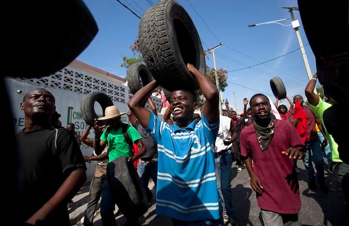 Anti-government protesters carry tires to use for burning road blocks in Port-au-Prince, Haiti, Saturday, Dec. 13, 2014. 