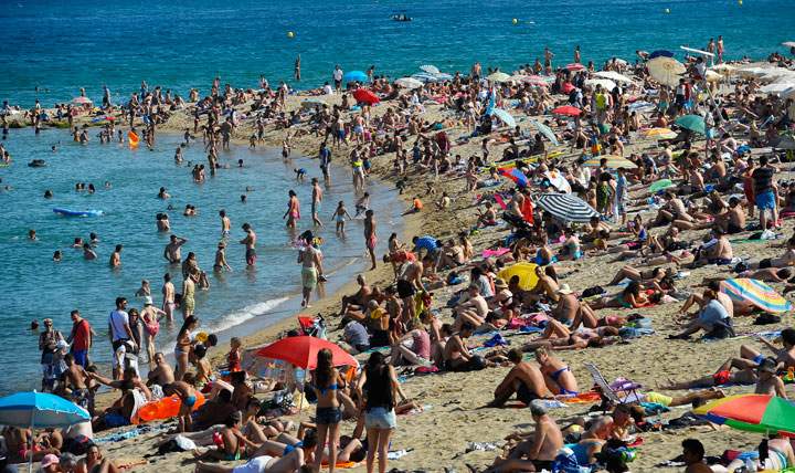 In this July 17, 2014 file photo, people relax on the beach, in Barcelona, Spain. Tourists and locals alike flock to beaches around the city, some of which are dotted with distinctive architecture.