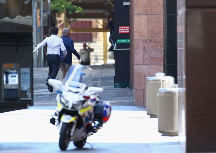Two hostages run to safety outside the Lindt Cafe, Martin Place on December 15, 2014 in Sydney, Australia.