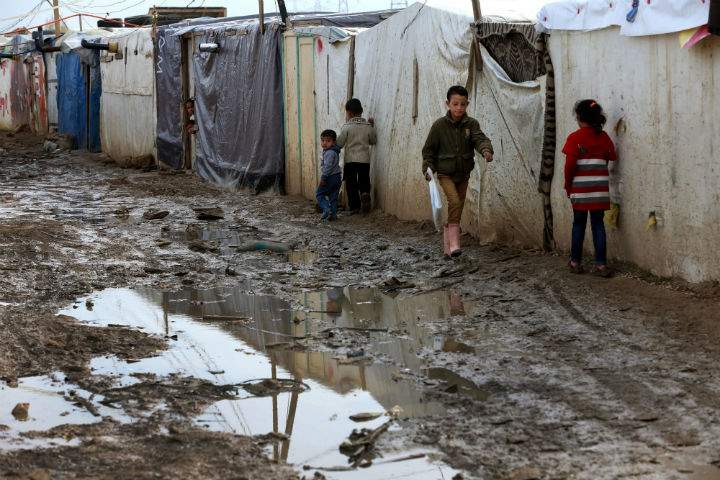 Syrian refugee children walk past tents at a refugee camp in the eastern Lebanese Town of Zahleh on Dec. 2, 2014. Lebanon is imposing strict visa restrictions for Syrians trying to enter the country.