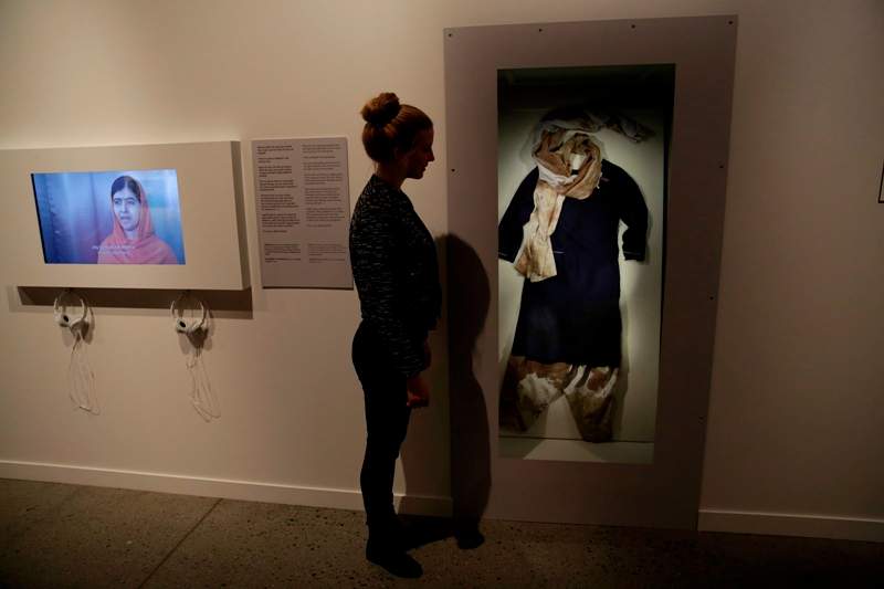 A Nobel Peace Center worker poses for photographs beside the blood stained school uniform joint Nobel Peace prize winner Malala Yousafzai was wearing when she was shot by the Taliban.