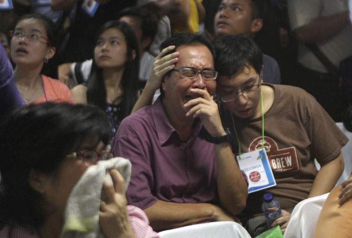 Relatives of passengers of the missing AirAsia flight react upon seeing the news on television about the findings of bodies on the waters near the site where the jetliner disappeared, at the crisis center at Juanda International Airport in Surabaya, East Java, Indonesia, Tuesday, Dec. 30, 2014.