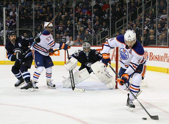  Taylor Hall #4 of the Edmonton Oilers plays the puck to the side of the net as teammate David Perron #57 positions himself between Mark Stuart #5 and goaltender Ondrej Pavelec #31 of the Winnipeg Jets during second period action on December 3, 2014 at the MTS Centre in Winnipeg, Manitoba, Canada. 