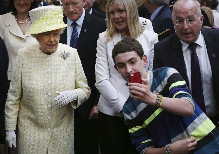 A boy takes a selfie in front of Queen Elizabeth II during a visit to St George’s indoor market in Belfast on Tuesday June 24, 2014.
