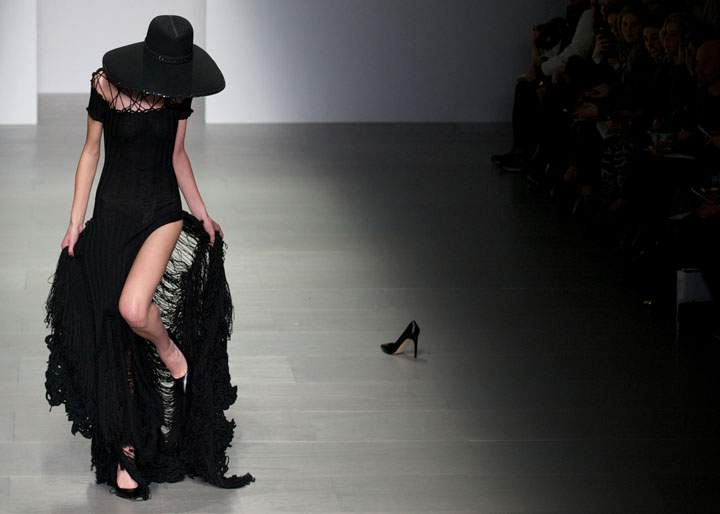 A model gets her shoe caught in her dress on the catwalk while a shoe of another model lies abandoned after a similar incident during a show for Fashion Week in London on February 15, 2014.