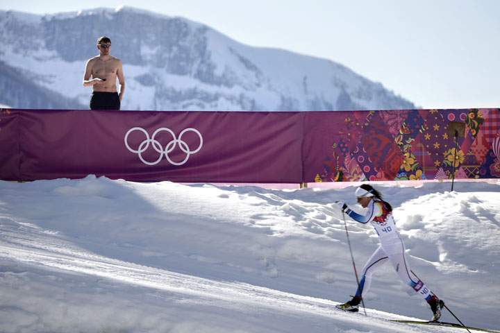 A shirtless spectator watches Sweden’s Charlotte Kalla compete during the women’s 10K classical style cross-country race at the 2014 Winter Olympics, Thursday, Feb. 13, 2014, in Russia.