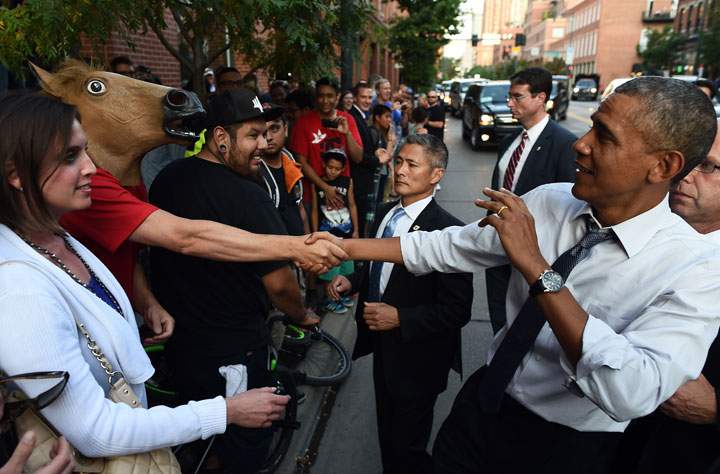 U.S. President Barack Obama jokingly reacts as he shakes hands with a man wearing a horse-head mask on a street in Denver, Colorado, on July 8, 2014.