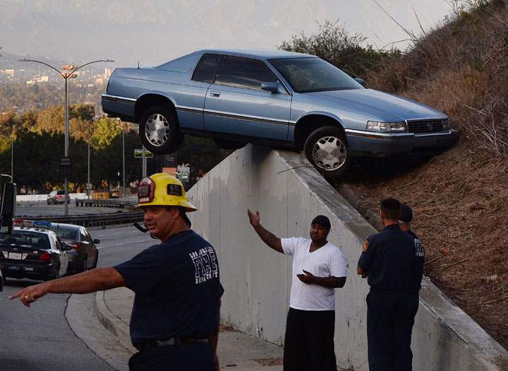 A car sits atop an embankment after the driver lost control on South La Brea Ave in Baldwin Hills, Los Angeles on August 24, 2014.