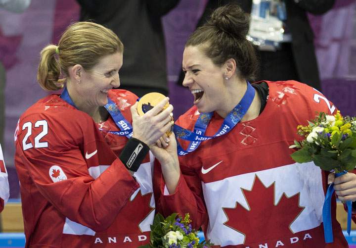 Canada’s Hayley Wickenheiser, left, and teammate Natalie Spooner admire their medals after beating the U.S. 3-2 in overtime in the women’s hockey final at the Sochi Winter Olympics Thursday, February 20, 2014 in Sochi.