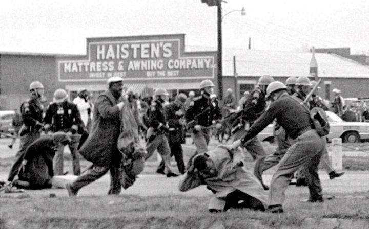 Alabama state troopers swing nightsticks to break up a civil rights voting march in Selma, Ala.