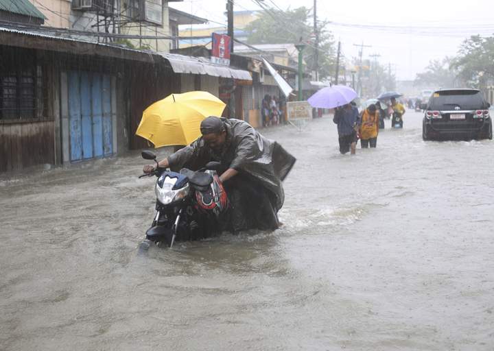 A man pushes his motorcycle along floodwaters bought by Typhoon Hagupit in Camarines Sur province, eastern Philippines Monday, Dec. 8, 2014.