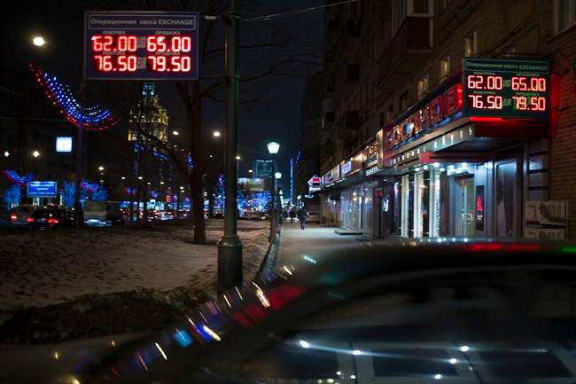 Signs advertising currencies light next to the exchange office in Moscow, Russia, Monday, Dec. 15, 2014. The price of crude oil continued to drop Monday, and Russia's ruble plunged to a record low against the dollar. The ruble crashed through 60 to the dollar, trading at 60.33 by early afternoon. (AP Photo/Pavel Golovkin).