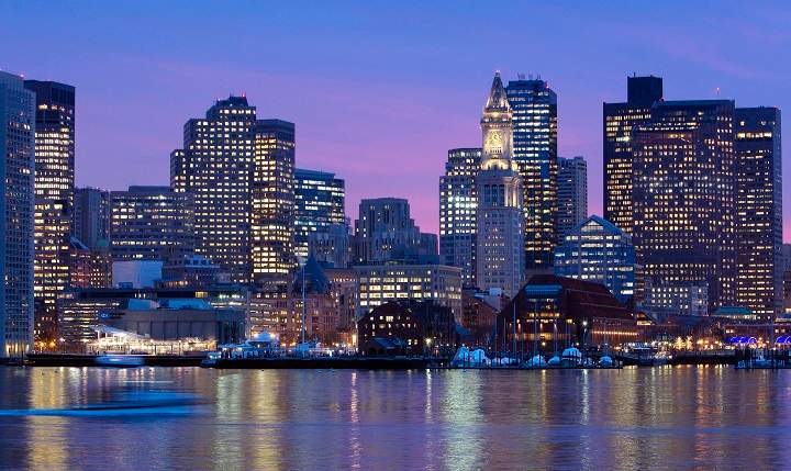 In this Jan. 6, 2012 file photo, the Boston city skyline is illuminated at dusk as it reflects off the waters of Boston Harbor. 