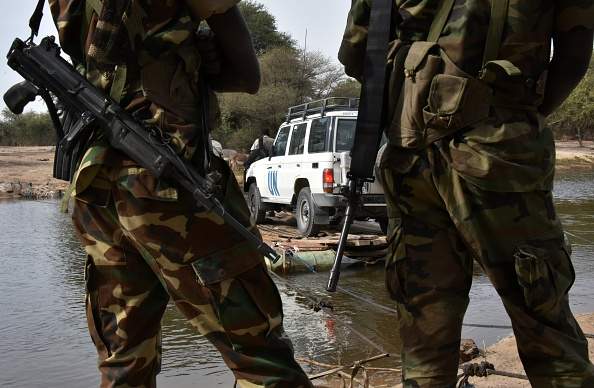 A picture taken on January 27, 2015 shows Chadian soldiers watching as a UN vehicle from a United Nations' refugee agency (UNHCR) convoy crosses a branch of lake Chad, heading to the UNHCR camp in N'Gouboua, in Chad's Lake Chad region. Since the beginning of January more than 14,000 people have fled over the Nigerian border into Chad to escape the bloody attacks by Islamist group Boko Haram around Baga, according to Mamadou Dian Balde, of the UN's refugee agency. 