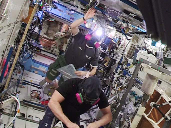 Astronauts Barry WiImore (foreground) and Terry Virts re-entered the U.S. segment wearing protective masks.