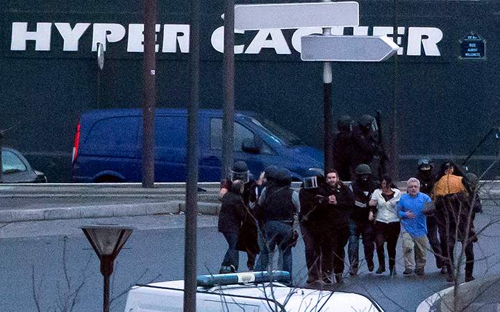 Security officers escort released hostages after they stormed a kosher market to end a hostage situation, Paris, Friday, Jan. 9, 2015.