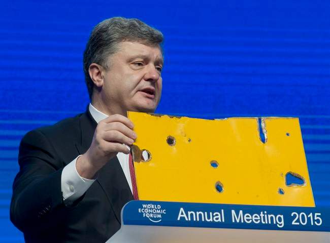 Ukrainian President Petro Poroshenko shows a piece of a Bus that was attacked recently during the panel "The Future of Ukraine" in Davos, Switzerland, Wednesday, Jan. 21, 2015.
