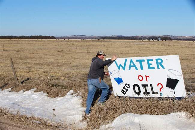 Land owner Jim Tarnick of Fullerton, Neb., who opposes the Keystone XL pipeline, hangs on to an anti-Keystone XL pipeline sign at the site where the planned pipeline is to go through his land, Friday, Jan. 16, 2015. 