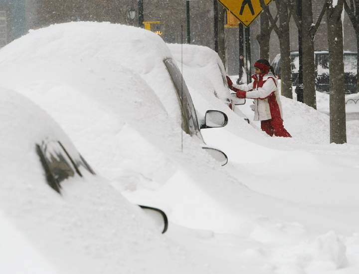 A girl wipes snow from a car during a fierce winter storm February 17, 2003 in New York City.