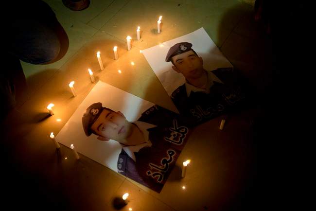 Members of Al-Kaseasbeh, the tribe of Jordanian pilot, Lt. Muath al-Kaseasbeh, who is held by the Islamic State group militants, light candles by posters with his picture in his home town of Karak, Jordan, Saturday, Jan. 31, 2015.