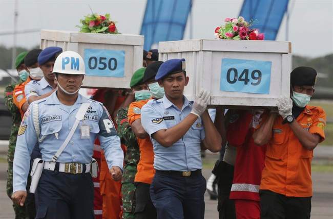 FILE - In this Monday, Jan. 19, 2015, file photo, members of the National Search and Rescue Agency carry coffins containing bodies of the victims aboard AirAsia Flight 8501 to transfer to Surabaya at the airport in Pangkalan Bun. (AP Photo/Achmad Ibrahim, File).
