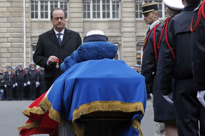 French President Francois Hollande holds a medal in front of the coffin of Police officer Clarissa Jean-Philippe during a ceremony to pay tribute to the three police officers killed in the attacks, in Paris, France, Tuesday, Jan. 13, 2015.