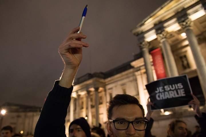 A woman holds up a phone with a sign on the screen reading ‘I am Charlie’ in French and a pen as she takes part in a vigil of people, including many who were French, to show solidarity with those killed in an attack at the Paris offices of weekly newspaper Charlie Hebdo, in Trafalgar Square, London, Wednesday, Jan. 7, 2015.