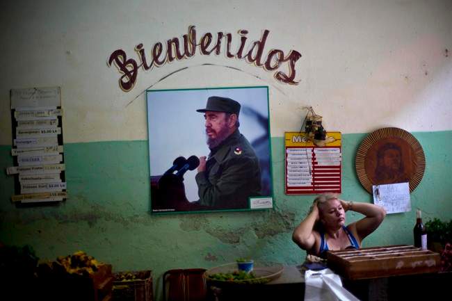 FILE - In this Dec. 26, 2014 file photo, a photograph of Fidel Castro hangs under the Spanish word "Welcome" on the wall at a state-run food market in Havana, Cuba.