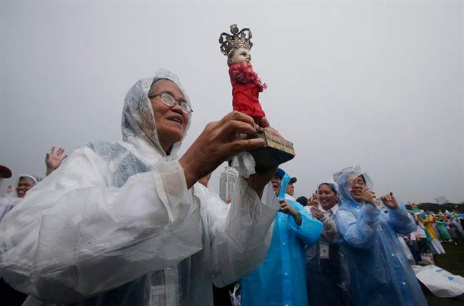 A nun holds the statue of the infant Jesus in the rain as Pope Francis celebrates his final Mass in Manila, Philippines, Sunday, Jan. 18, 2015.