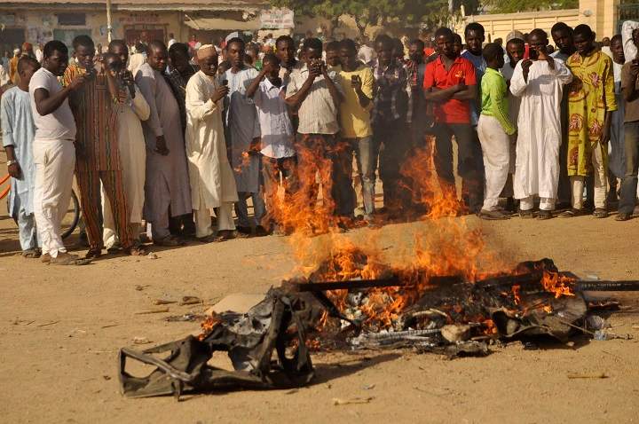 In this file photo taken Friday, Nov. 28, 2014, people gather at the site of a bomb explosion in an area known to be  targeted by the militant group Boko Haram  in Kano, Nigeria. 