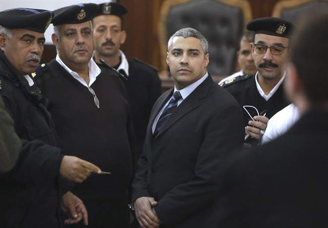 Canadian Al Jazeera English journalist Mohamed Fahmy, speaks with policemen during his retrial in Cairo, Egypt, Monday, Feb. 23, 2015. The retrial of two Al-Jazeera English journalists who face terror-related charges in a case widely criticized by human rights organizations and media groups has been postponed to March 8. 