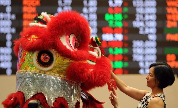 A performer donning a lion dance costume, tries to pick up red “lai see” envelopes from employees at the Philippine stock exchange during Lunar New Year of the Sheep celebrations in Manila on February 18, 2015.