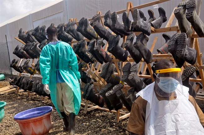 Health care workers walk past boots that were washed to prevent the spread of the Ebola virus inside a USAID, funded Ebola clinic in Monrovia, Liberia, Friday, Jan. 30, 2015.