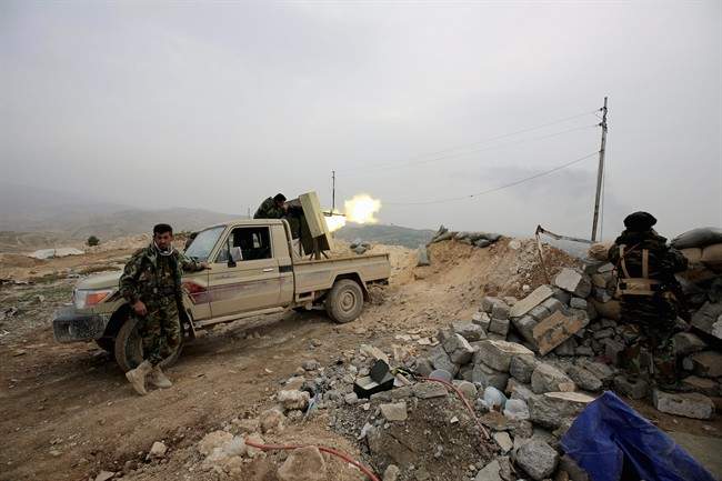 In this Jan. 29, 2015 photo, a Kurdish peshmerga fighter fires toward positions of the Islamic State group near Sinjar, once home to many of Iraq’s Yazidi religious minority.