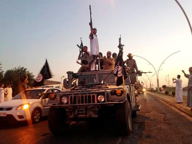 In this photo taken Monday, June 23, 2014, fighters from the Islamic State group parade in a commandeered Iraqi security forces armored vehicle down a main road in Mosul, Iraq.