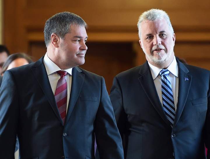 Education Minister Yves Bolduc, left, walks with Quebec Premier Philippe Couillard on their way to a caucus meeting, Thursday, February 26, 2015 at the legislature in Quebec City. Bolduc told the caucus he is resigning from politics.