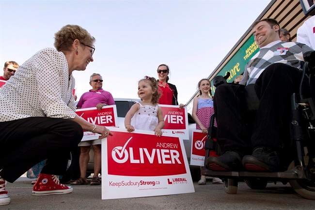 Ontario Liberal Leader Kathleen Wynne greets two-year-old Ella Prosperi as she arrives at a campaign event for candidate Andrew Olivier (right) in Sudbury, Ont. on Tuesday May 27, 2014, 2014. Elections Ontario has come to the ``unprecedented'' conclusion that the actions of two Liberals, including the premier's deputy chief of staff, constitute an ``apparent contravention'' of a bribery section of the Election Act.