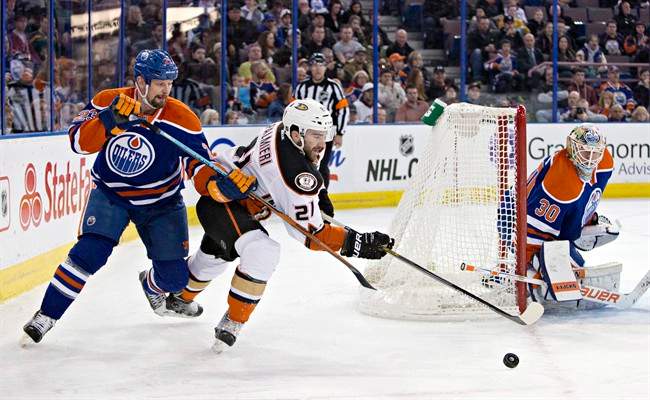 Anaheim Ducks' Kyle Palmieri (21) and Edmonton Oilers' Matt Hendricks (23) battle for the puck as goalie Ben Scrivens (30) keeps an eye on the play during first period NHL hockey action in Edmonton, Alta., on Saturday February 21, 2015.