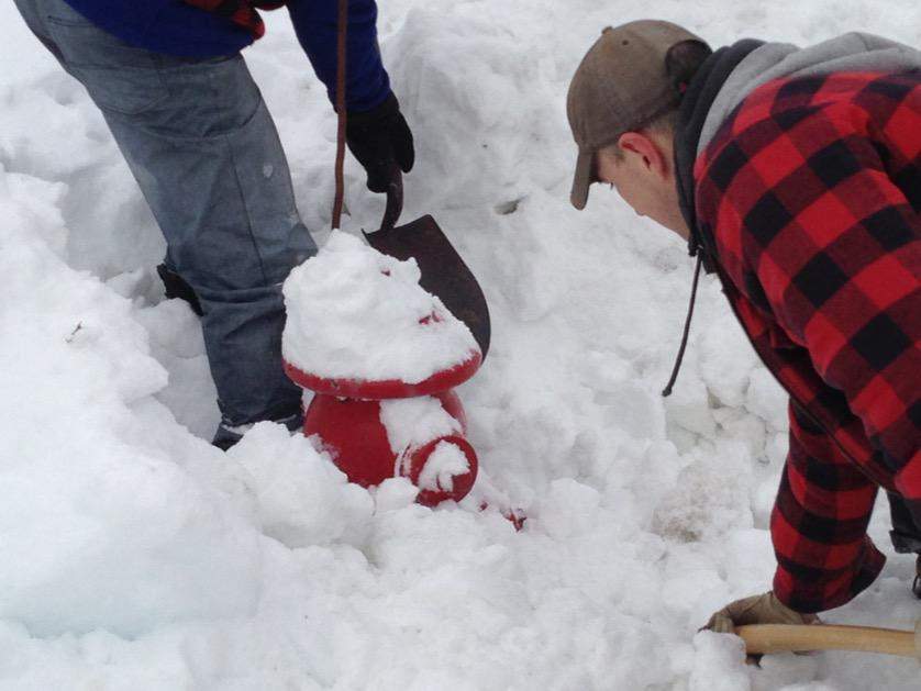 Off-duty firemen clear a fire hydrant covered in snow in Dartmouth.