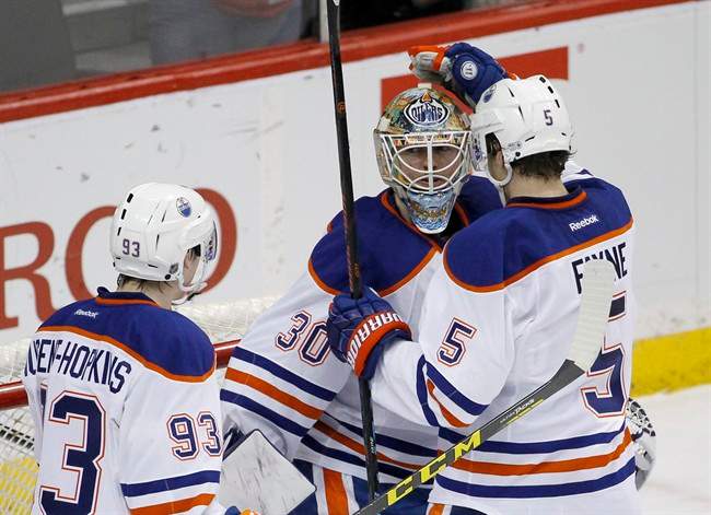 Edmonton Oilers defenseman Mark Fayne (5) and center Ryan Nugent-Hopkins (93) celebrate with goalie Ben Scrivens (30) after the Oilers defeated the Minnesota Wild 2-1 in an NHL hockey game in St. Paul, Minn., Tuesday, Feb. 24, 2015. 