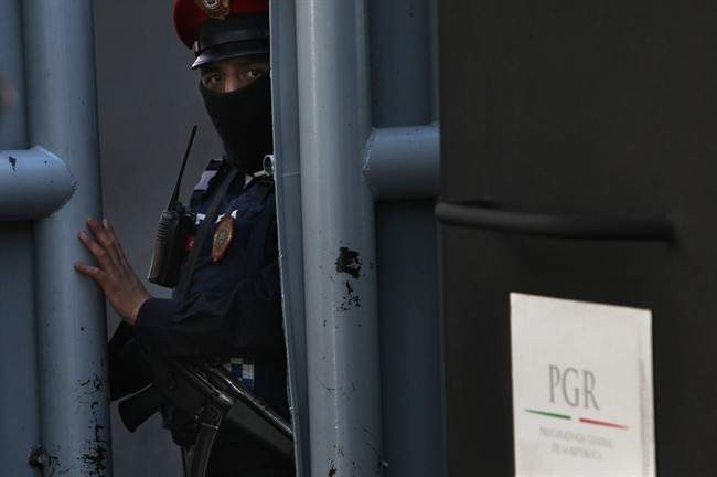 A masked federal police officer stands guard as part of increased security at the organized-crime division of Mexico's Attorney General Office where high profile detainees are sometimes held and shown to the press in Mexico City, Friday, Feb. 27, 2015. 