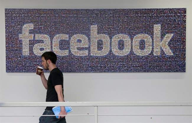  In this March 15, 2013, file photo, a Facebook employee walks past a sign at Facebook headquarters in Menlo Park, Calif. 