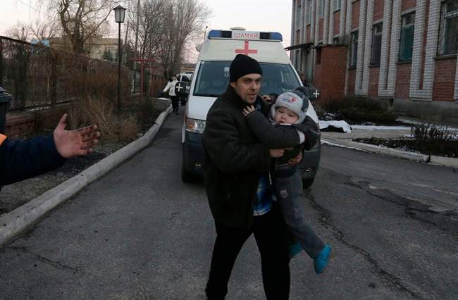 A man carries a child after shelling between Russia-backed separatists and Ukrainian government forces in a residential area of the town of Artemivsk, Ukraine, Friday, Feb. 13, 2015. 