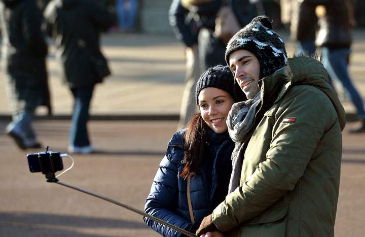 Tourists use a selfie stick to take a self-portrait.